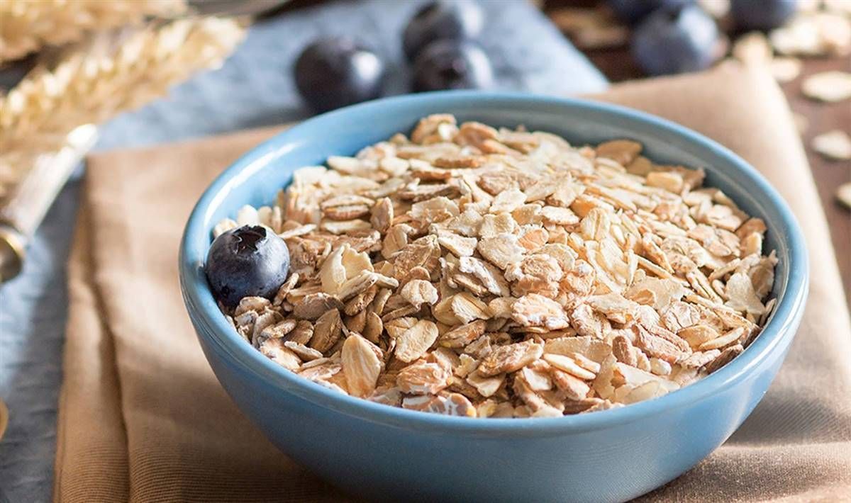 Tazón azul de avena con arándanos, sobre una servilleta beige.
