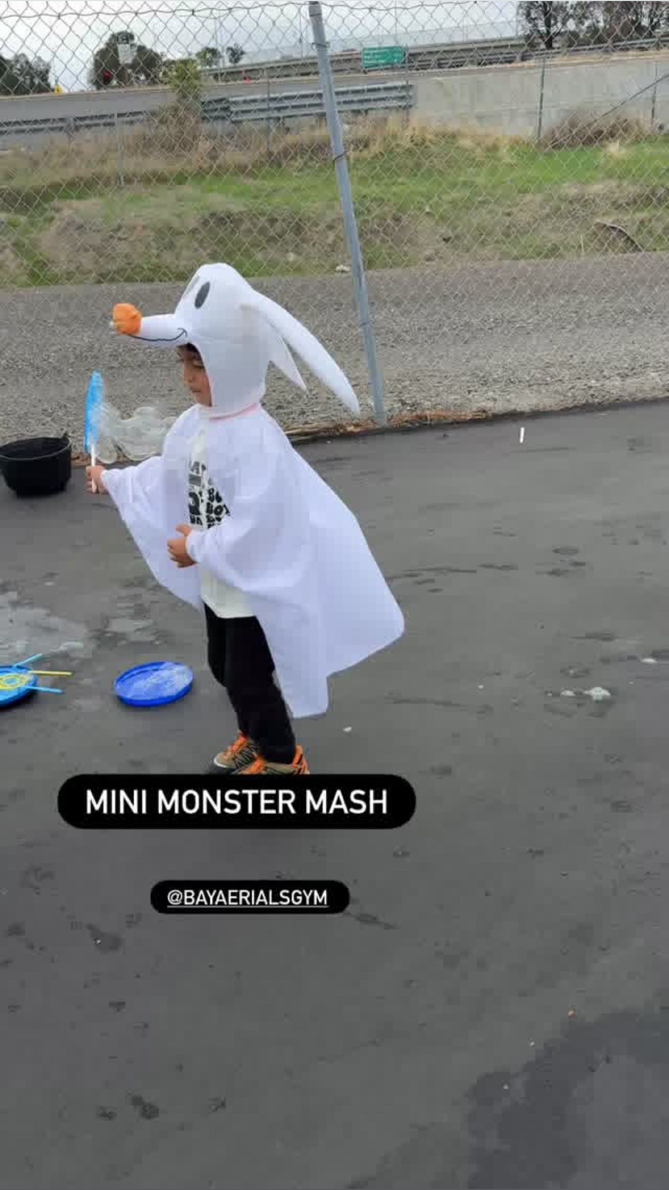 Child in a Zero costume from The Nightmare Before Christmas, playing with bubbles outside.