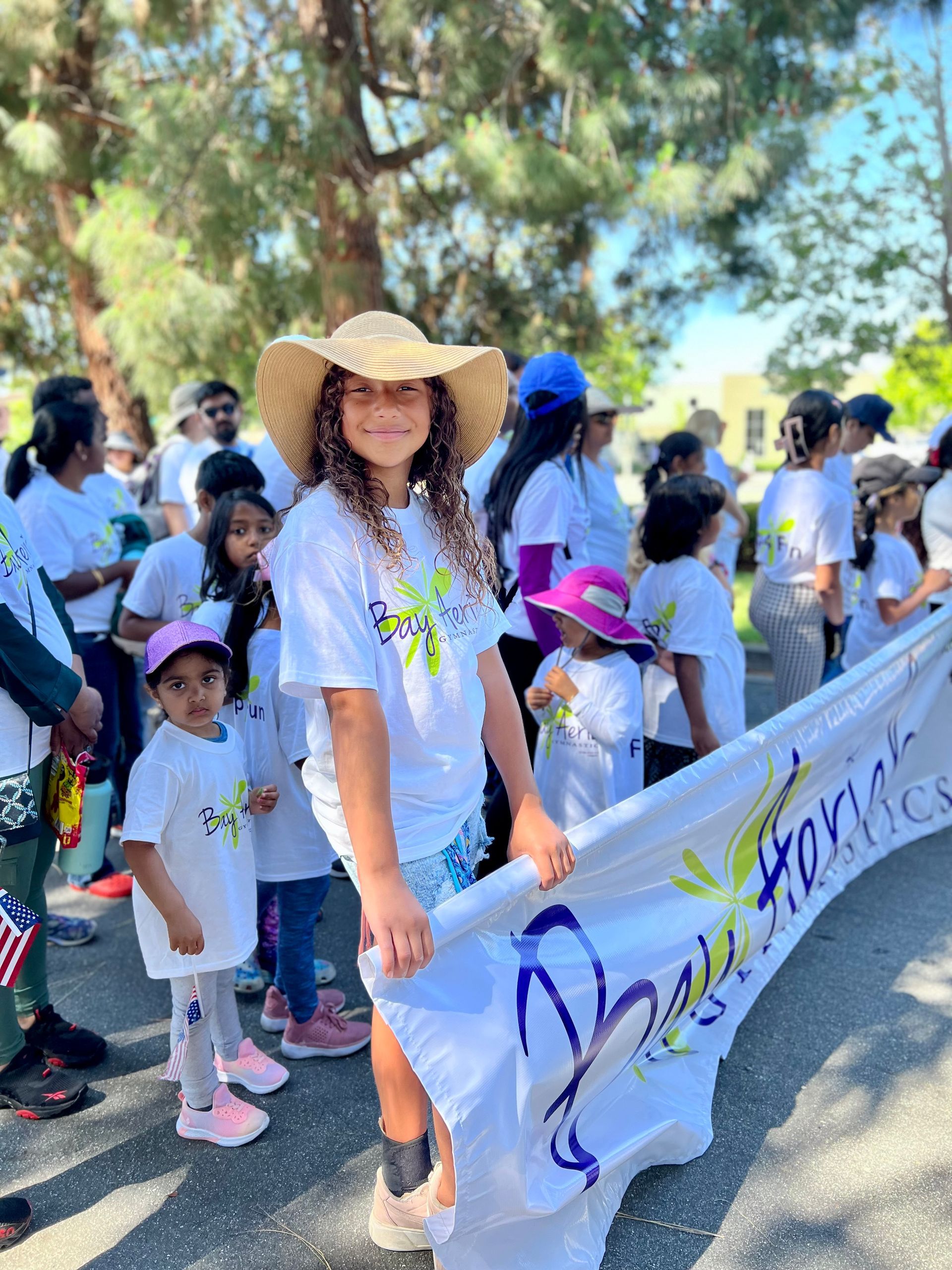 Group of people holding a banner at an outdoor event on a sunny day.