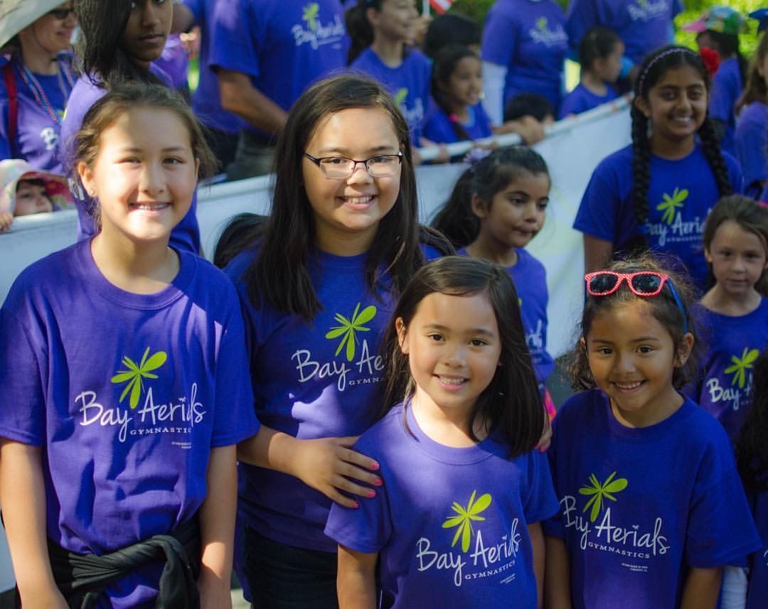 Children in matching blue shirts smile for the camera at a Bay Area event.