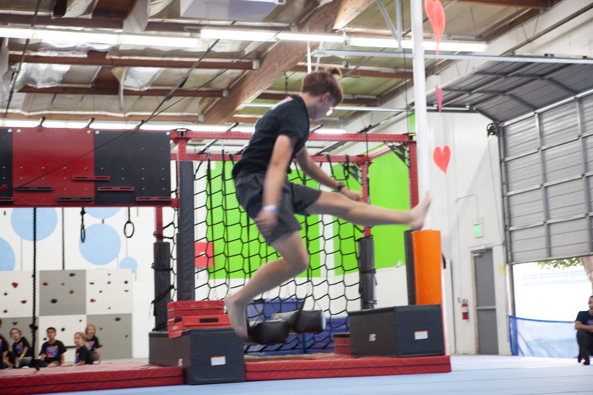 A person jumps over obstacles in an indoor obstacle course.