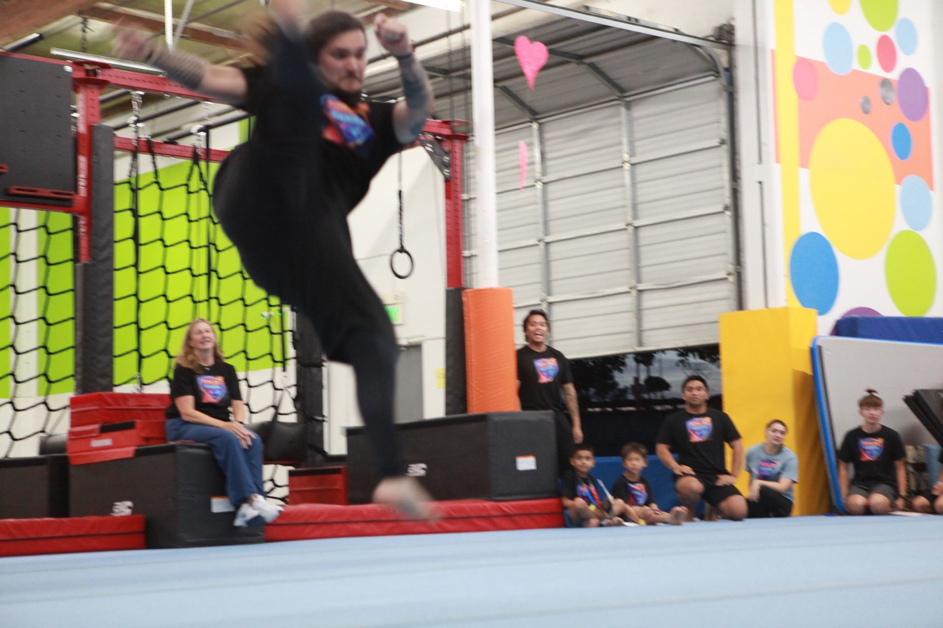 Person jumping in a gym setting with observers.