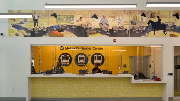 Interior of a service center with orange counter, glass windows, and a mural above the wall