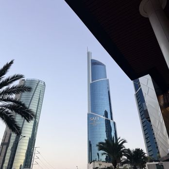 Modern glass skyscrapers and palm trees at dusk in a city skyline