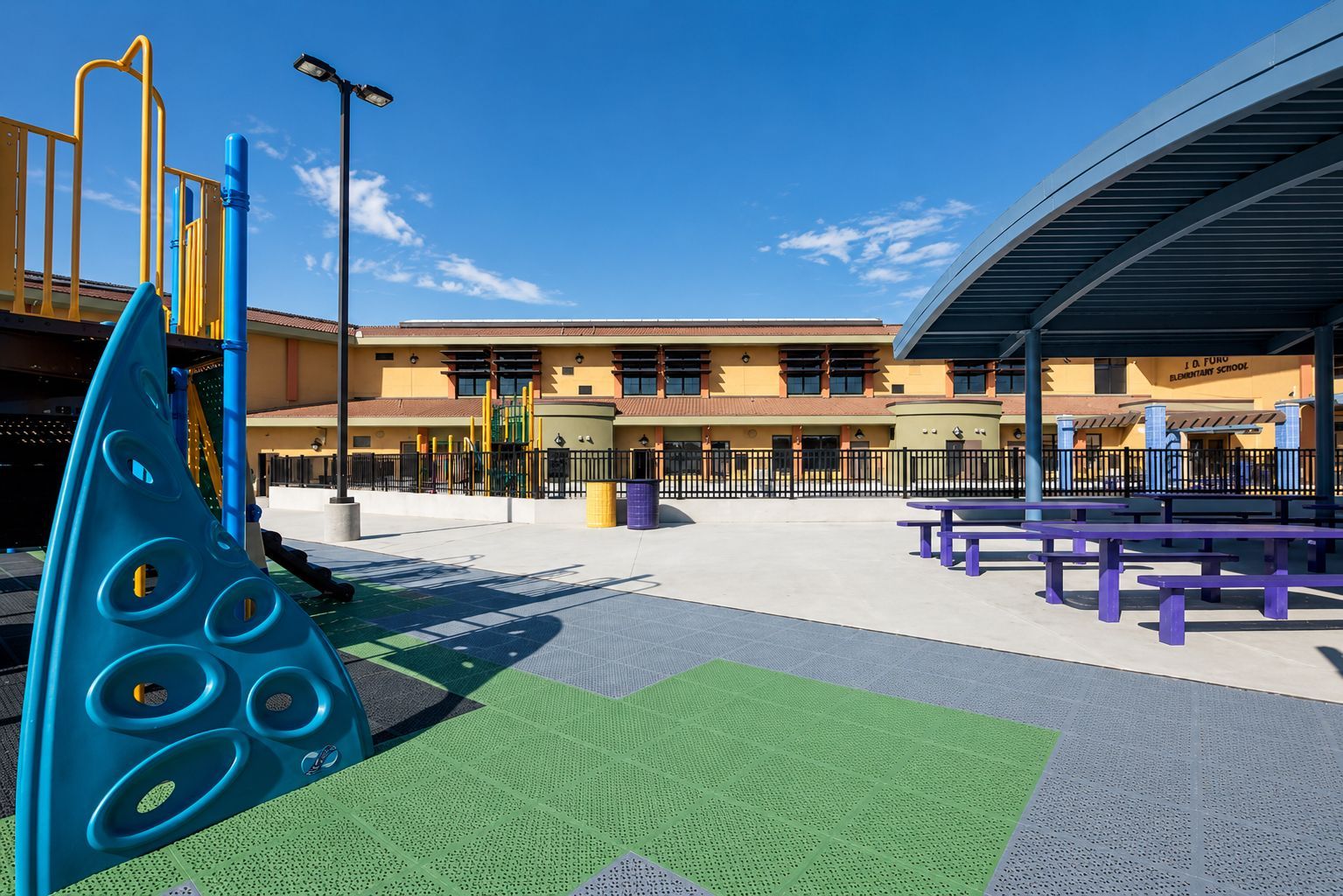 Modern building entrance with a curved canopy, glass facade, and landscaped walkway at sunset