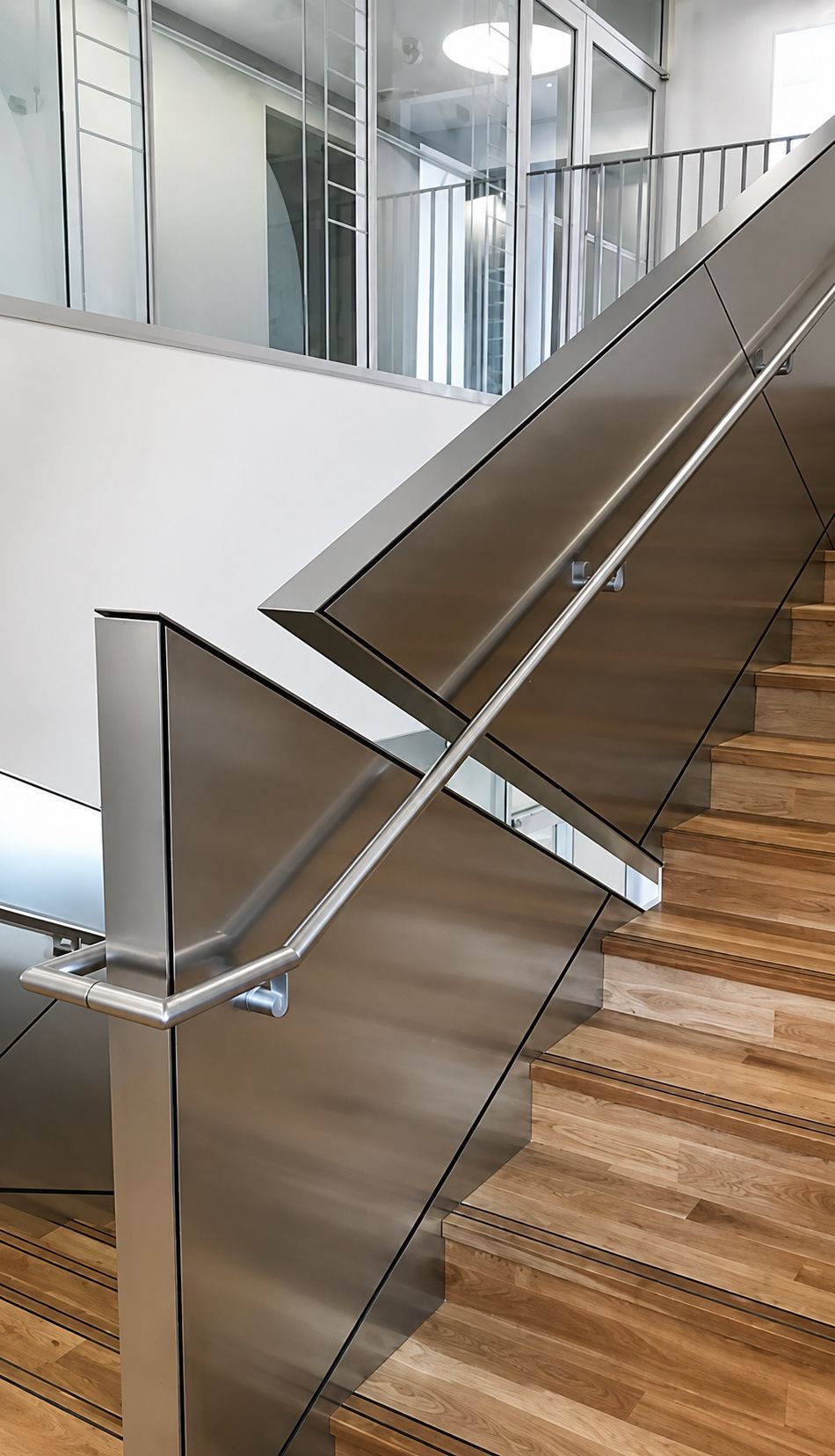 Staircase with wooden steps and stainless steel handrails in a modern indoor building
