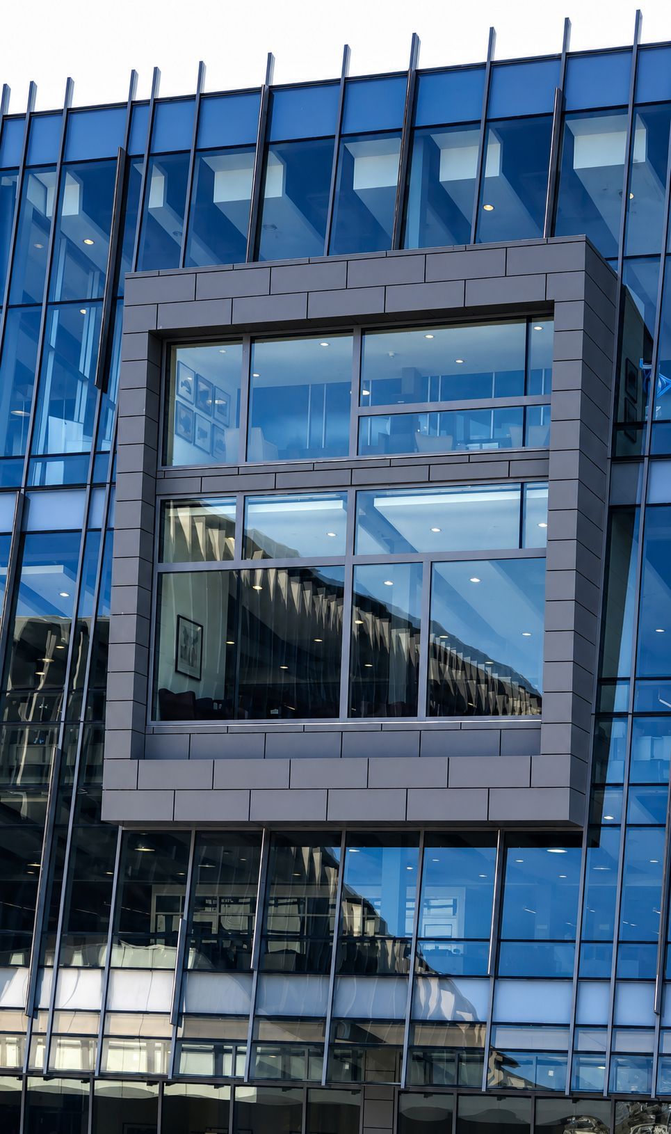 Glass building facade with a square window framed in gray panels.