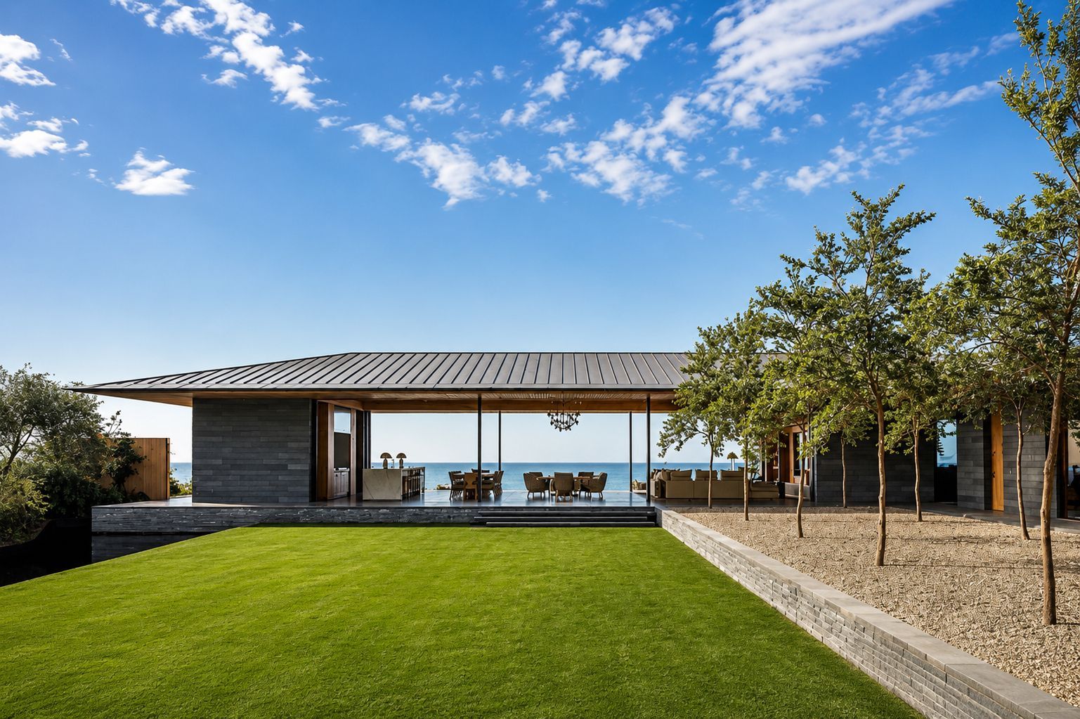 Modern building entrance with a curved canopy, glass facade, and landscaped walkway at sunset