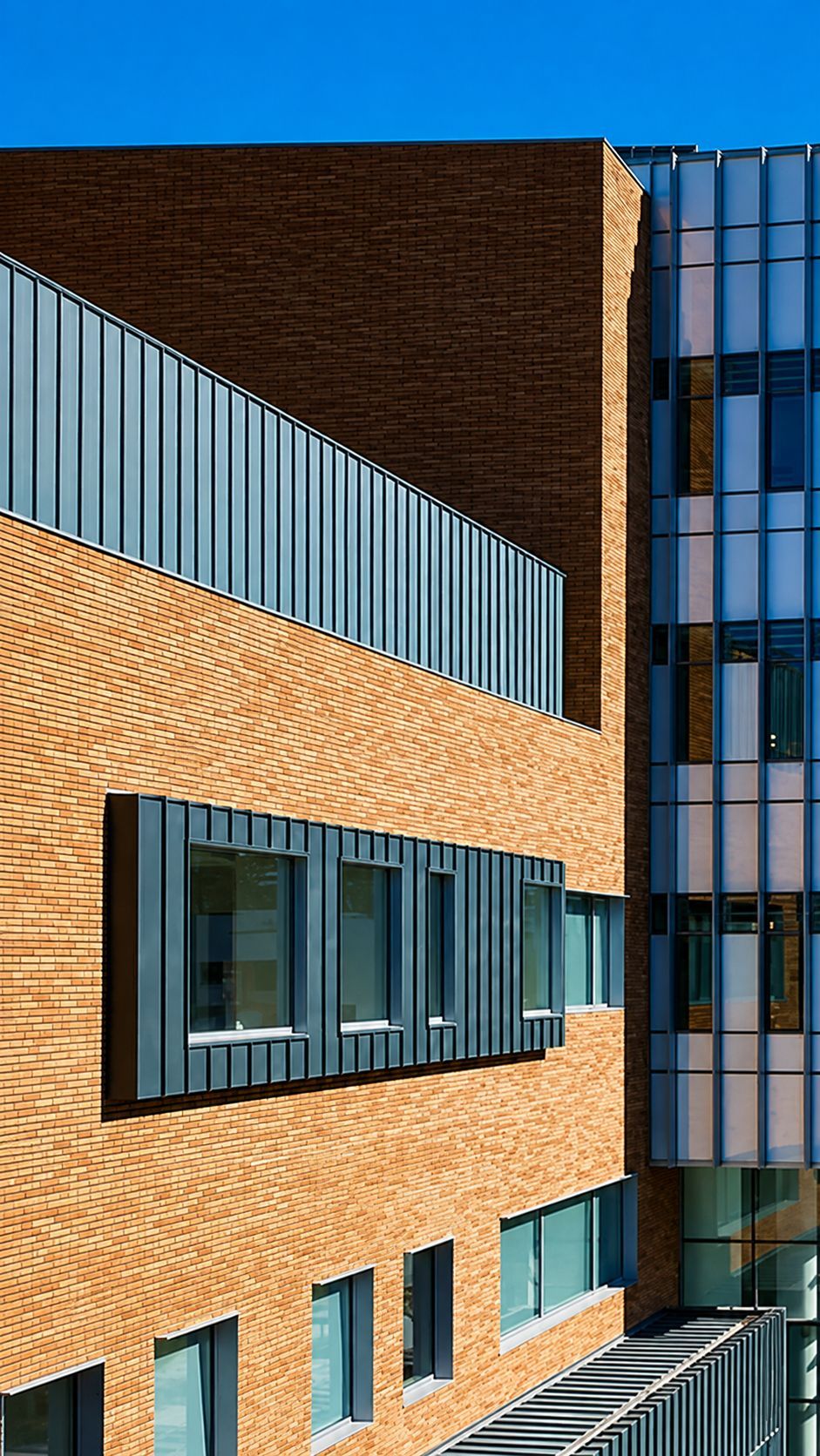 Modern brick and glass building exterior with large windows under a clear blue sky