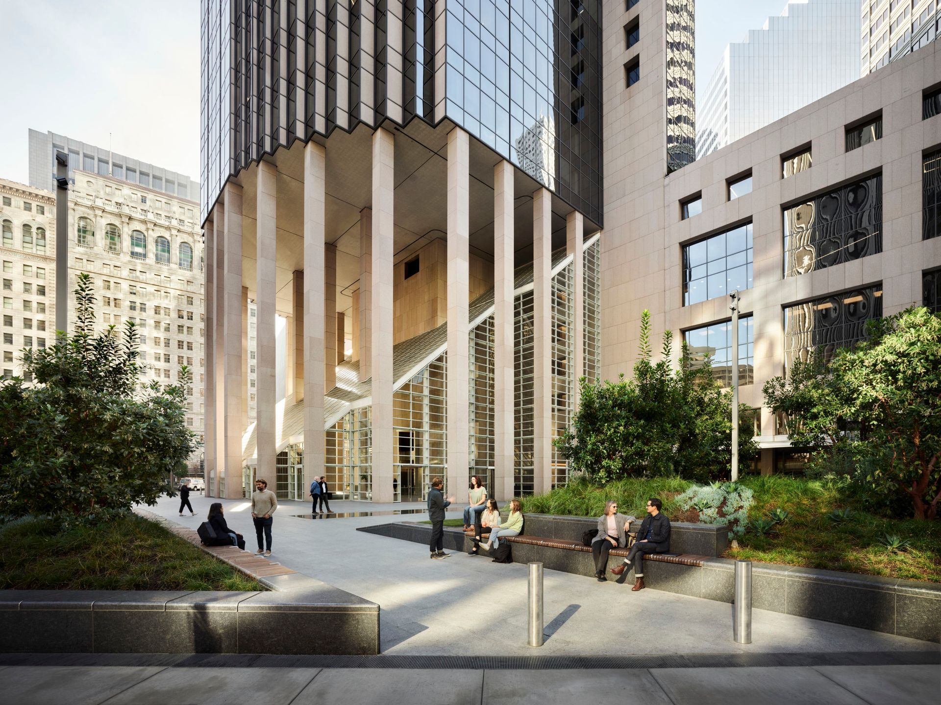Modern office plaza with people walking and sitting among trees, fountains, and tall buildings