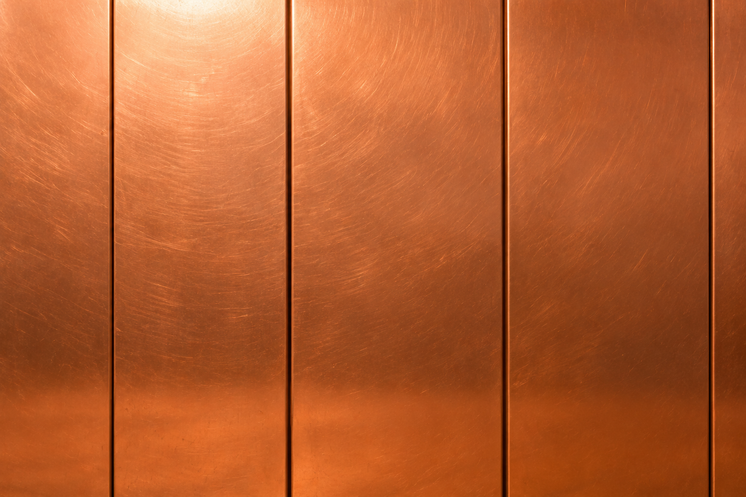 Copper-colored paneled wall with vertical seams and a warm metallic sheen