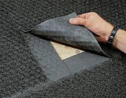 Hand lifting black roofing membrane to reveal beige underlayment on a roof deck