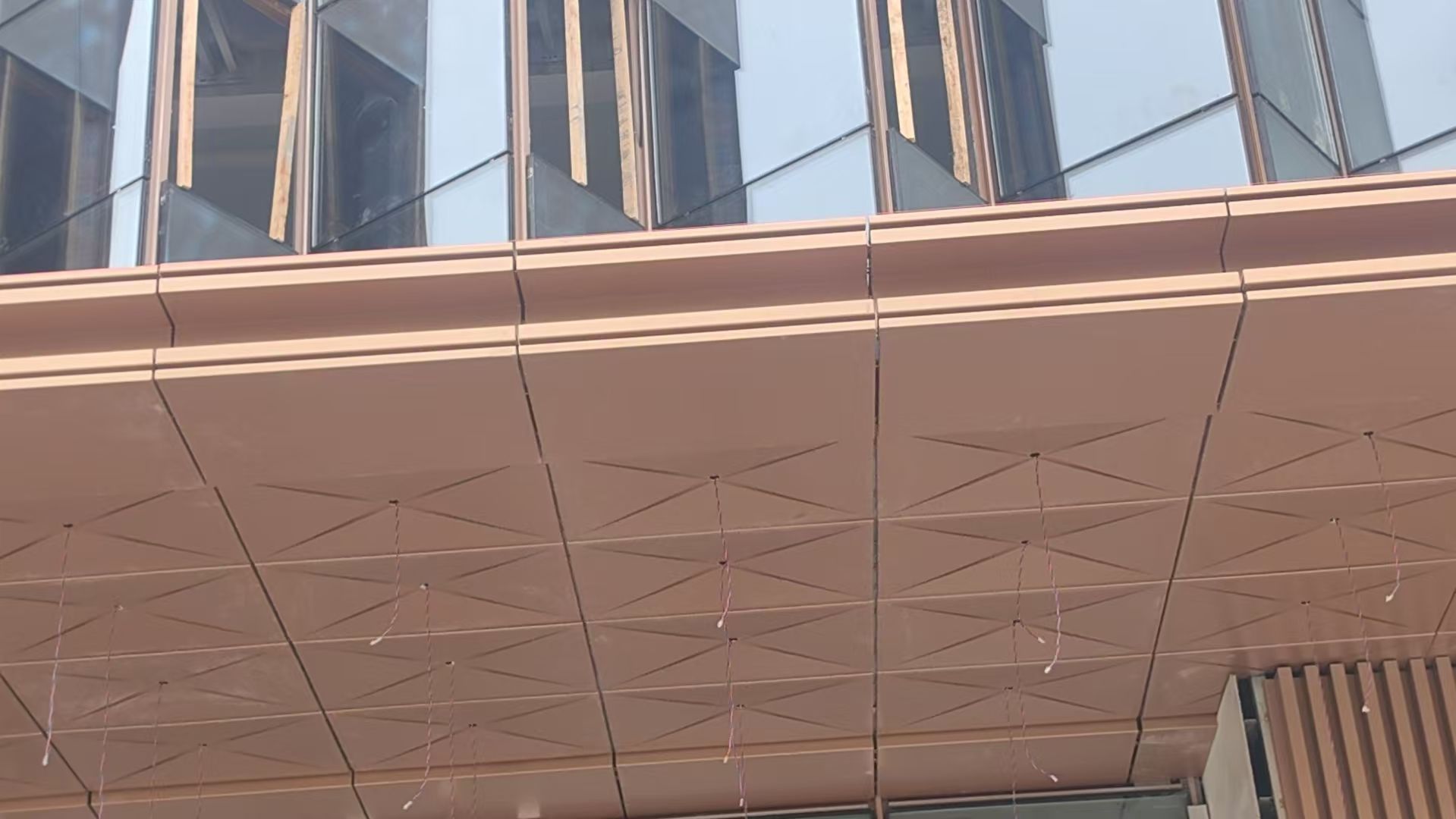 Modern building facade with reflective glass and a curved beige overhang underside.