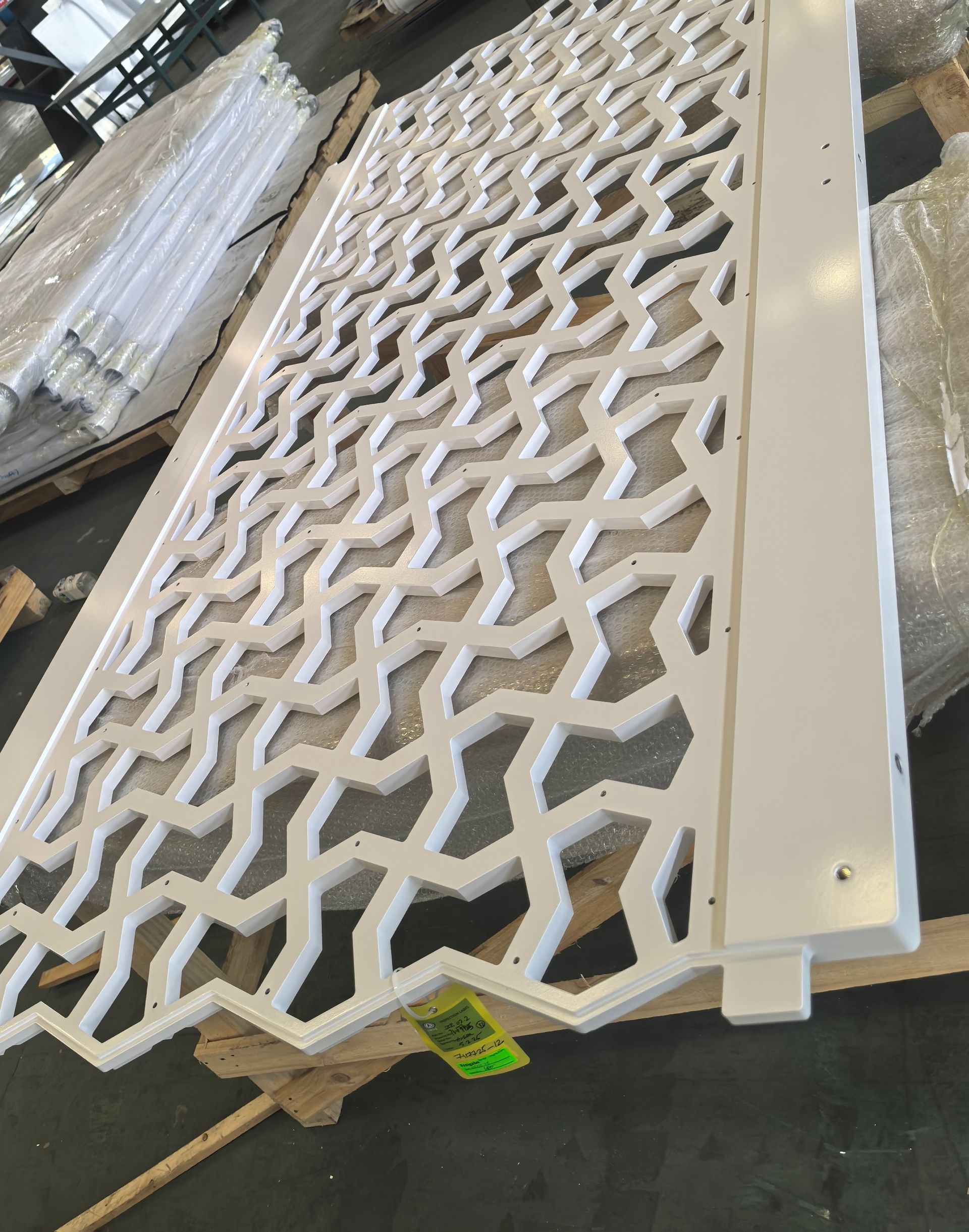 White decorative lattice panel leaning on a pallet in a warehouse-like setting