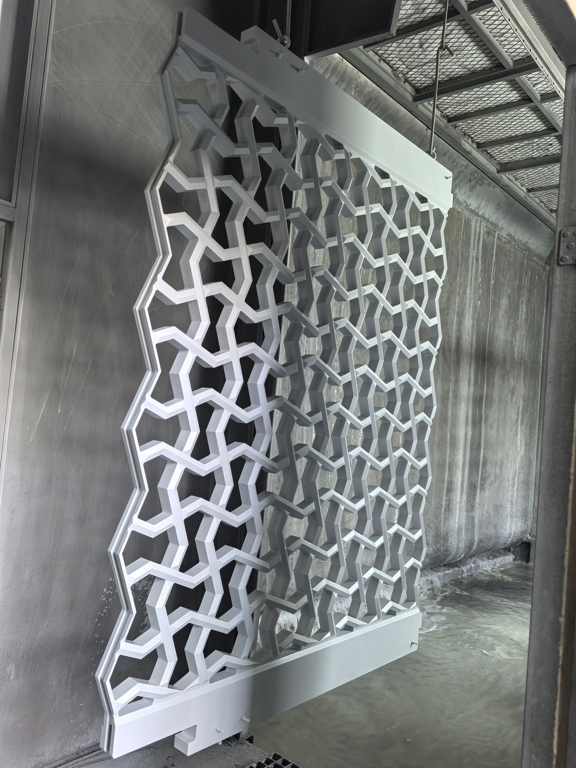 White geometric lattice panel leaning in an unfinished concrete interior corridor.