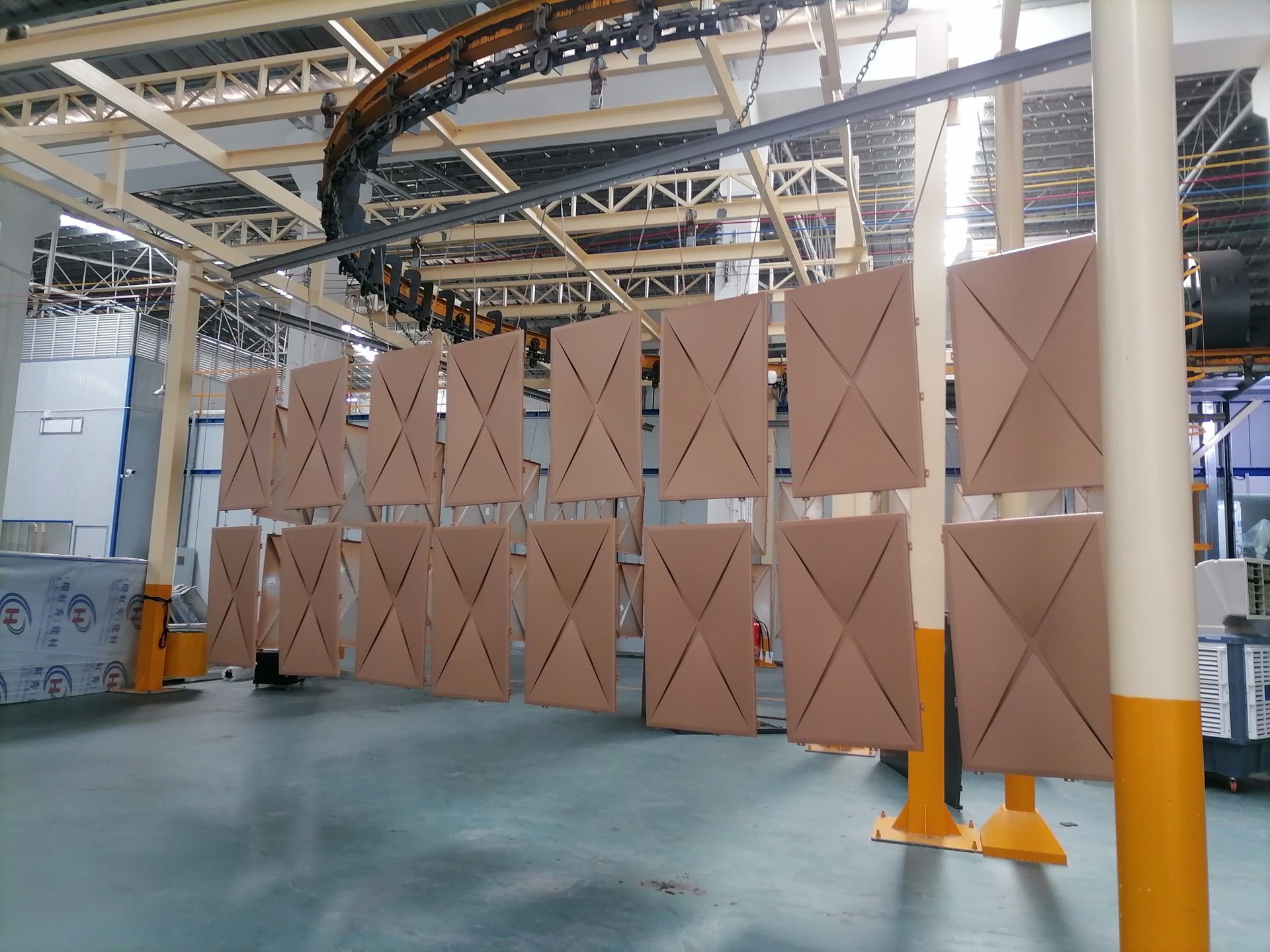 Large tan industrial curtains hanging in a factory or warehouse interior.