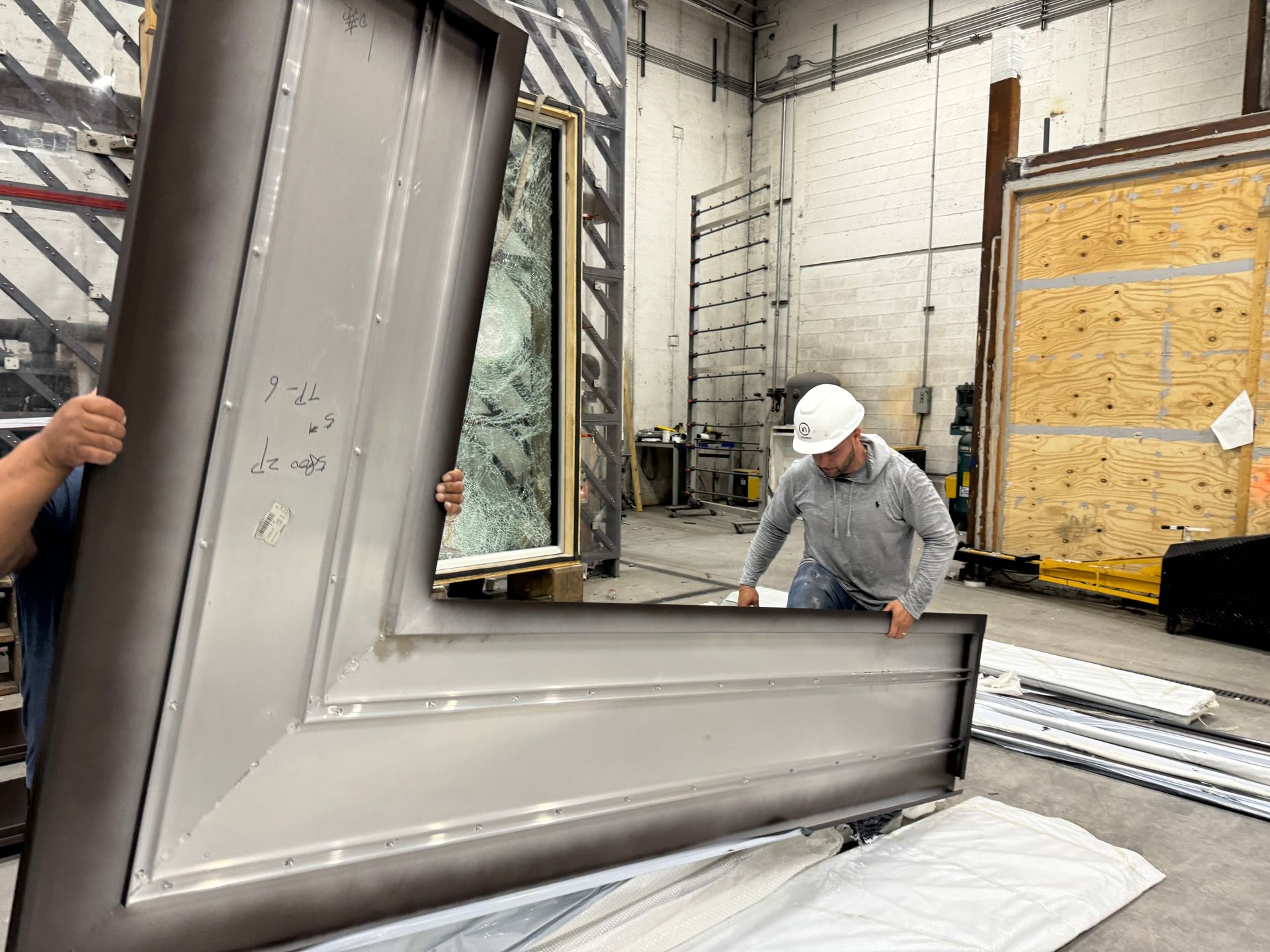 Worker moving a large gray framed panel in an industrial workshop