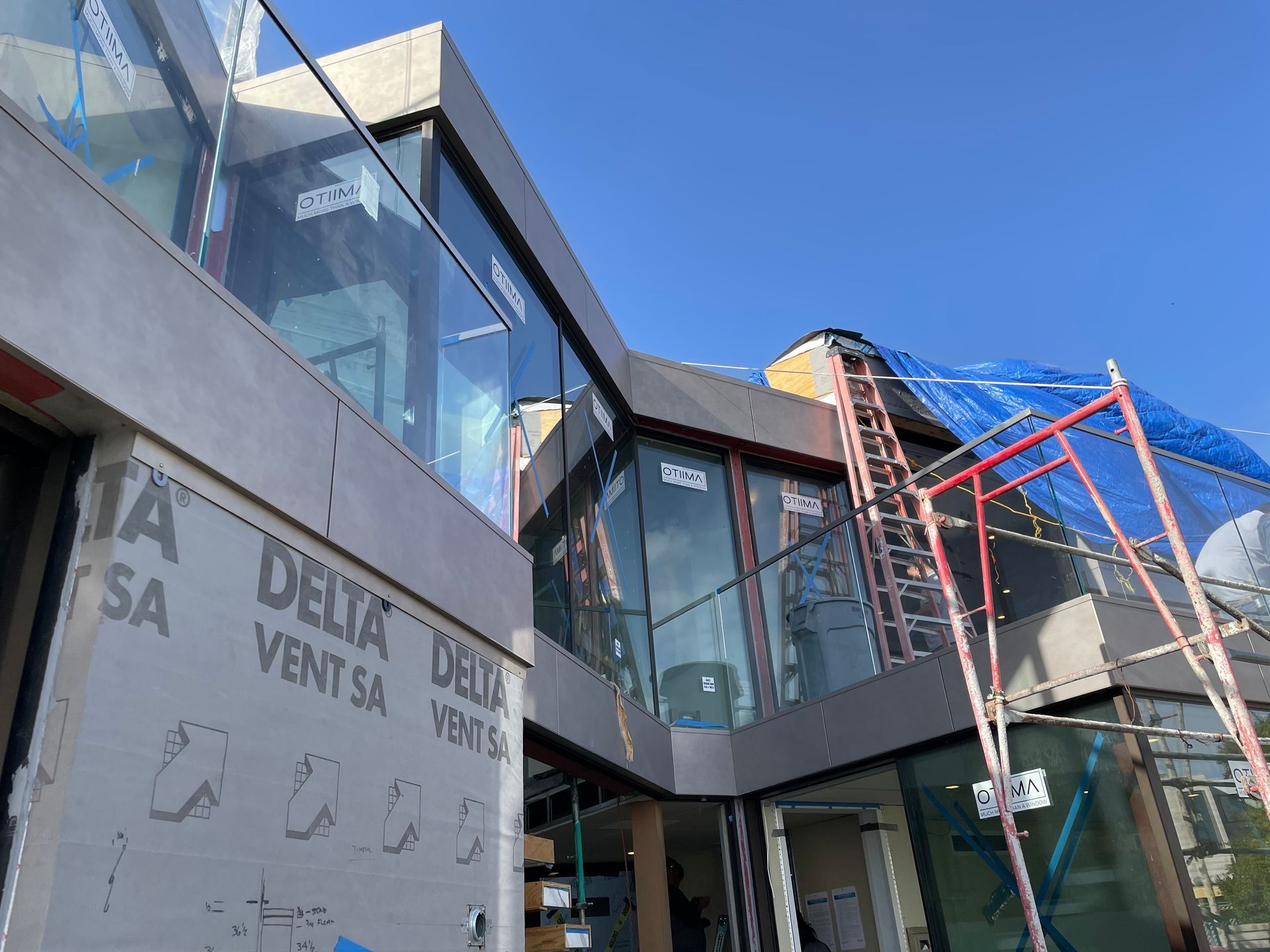 Modern building exterior with glass balconies, gray concrete, and blue sky overhead