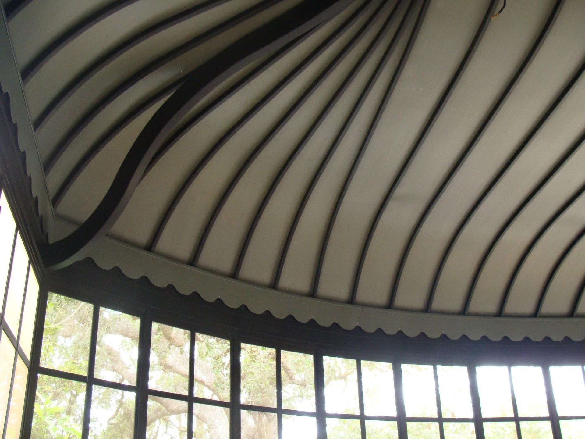 Curved black-and-white striped canopy above a row of tall windows in a bright interior
