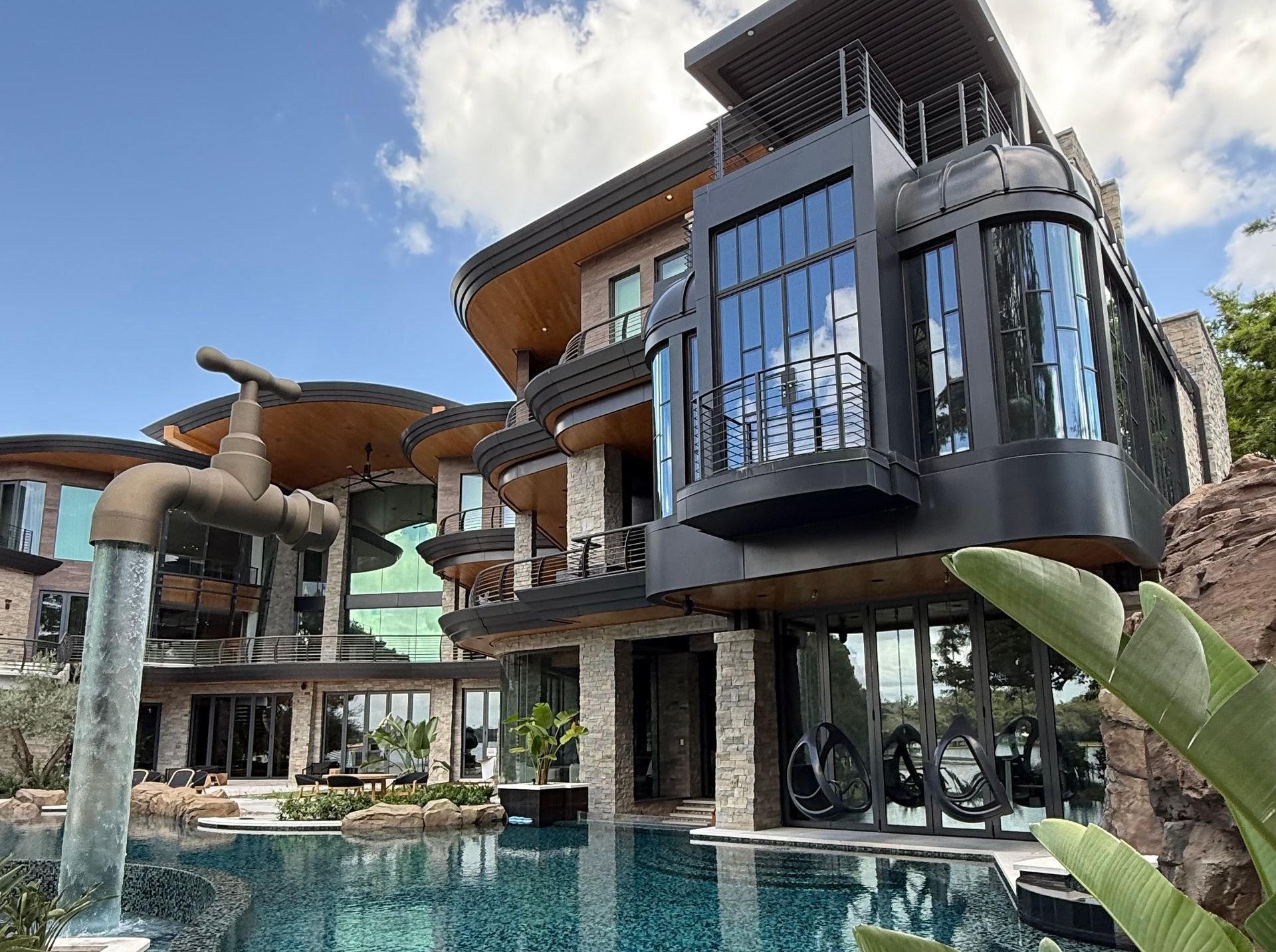 Luxury resort with modern glass buildings and a pool under a blue sky