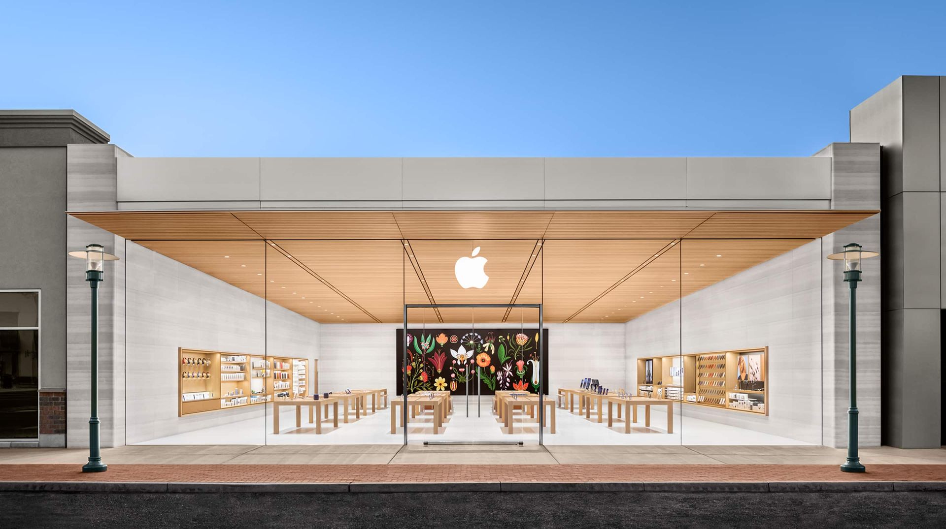 Apple Store storefront with glass entrance, illuminated interior, and blue sky above