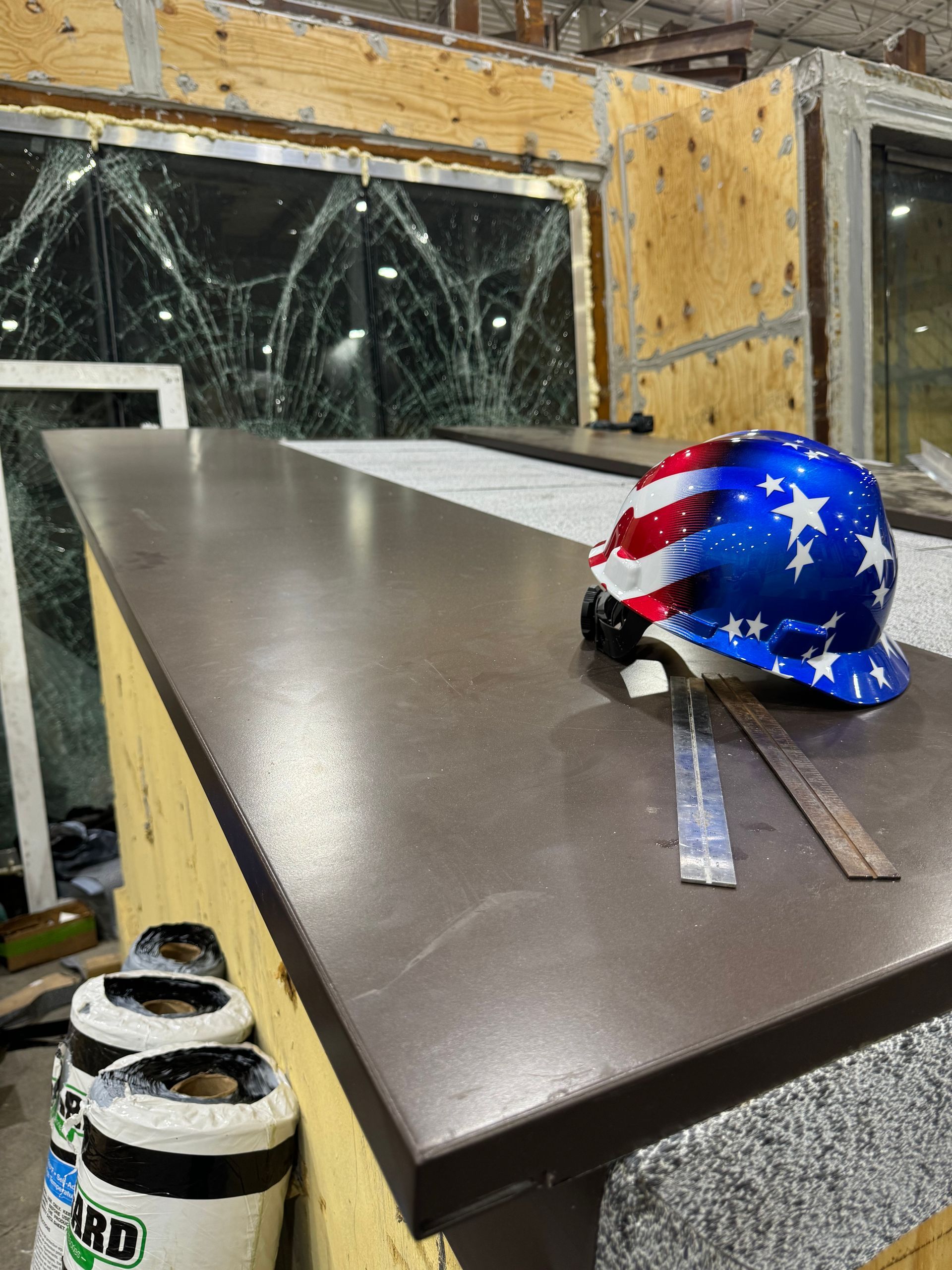 American flag hard hat on a workbench in a workshop with broken windows and debris
