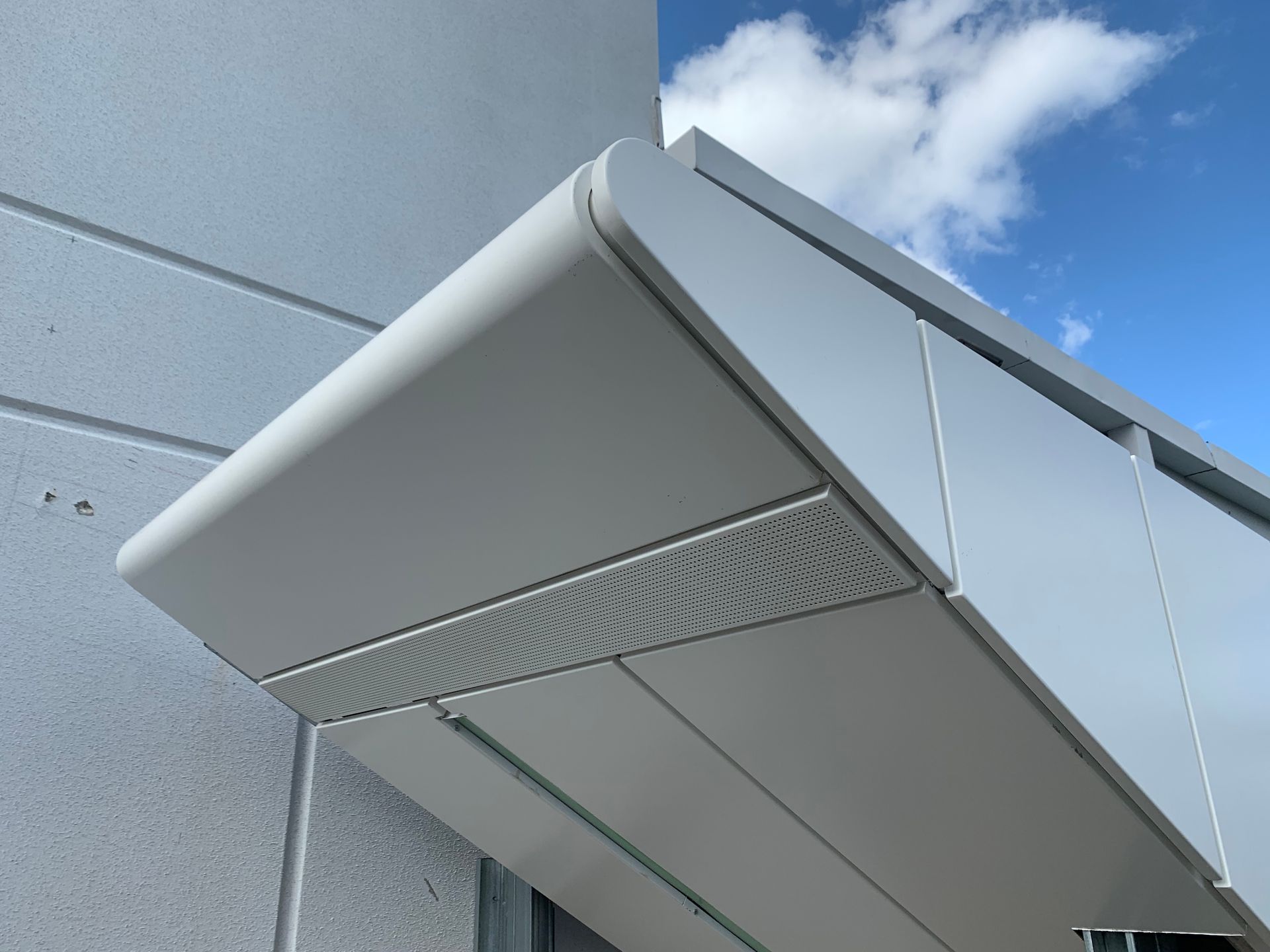 Modern building facade with a metallic awning against a blue sky