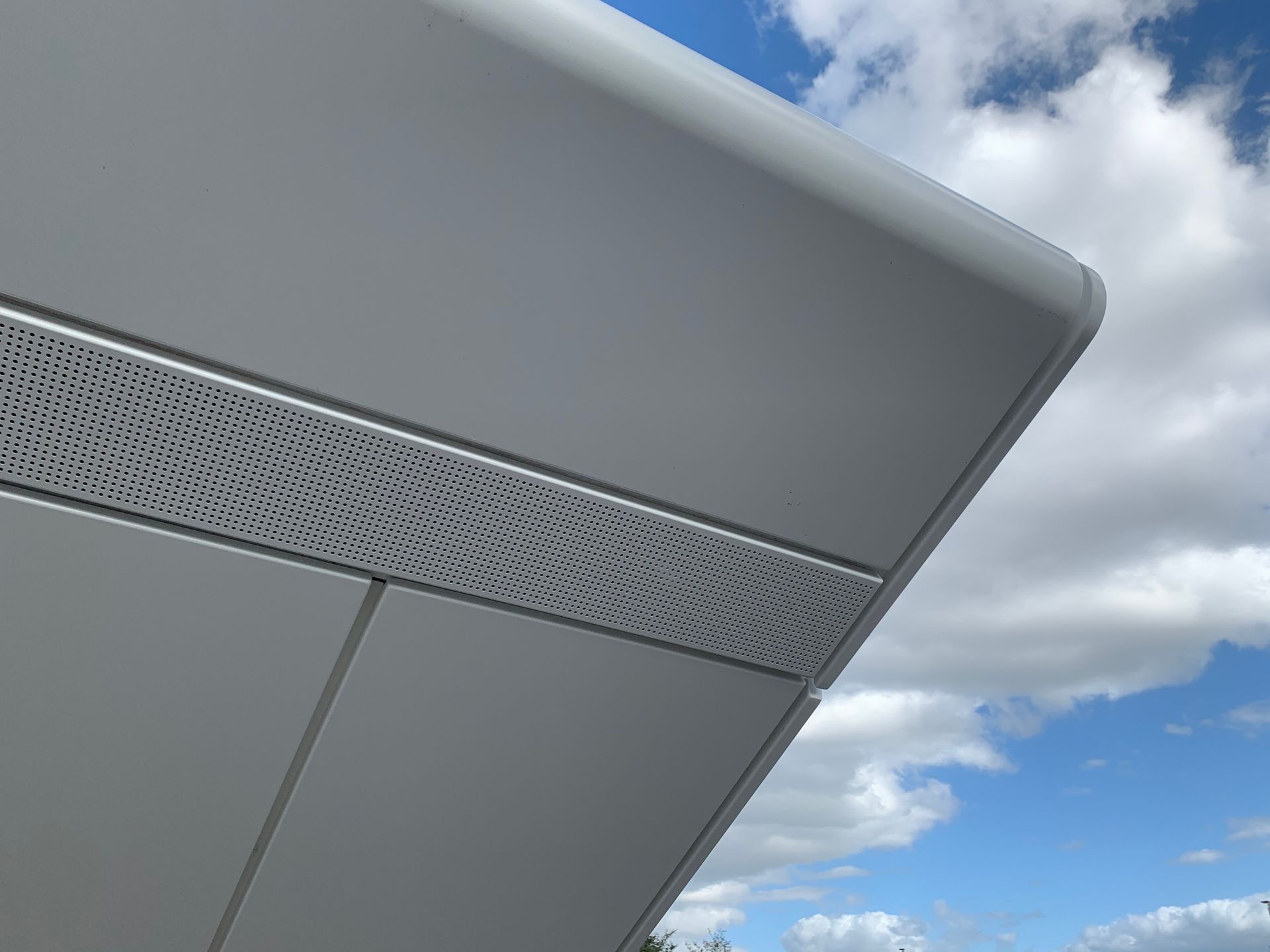 Close-up of a gray metal structure against a blue sky with clouds.