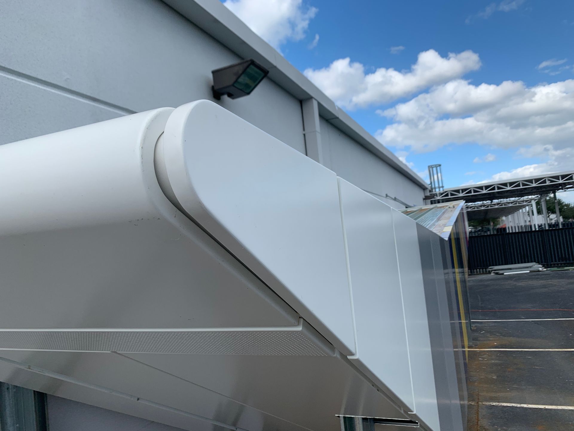 White retractable awning mounted on a building exterior under a blue sky with clouds