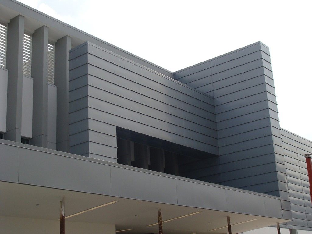 Modern gray building facade with vertical slats and a dark recessed entrance