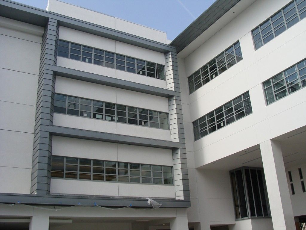 Modern white multi-story building with rows of windows and an open courtyard view