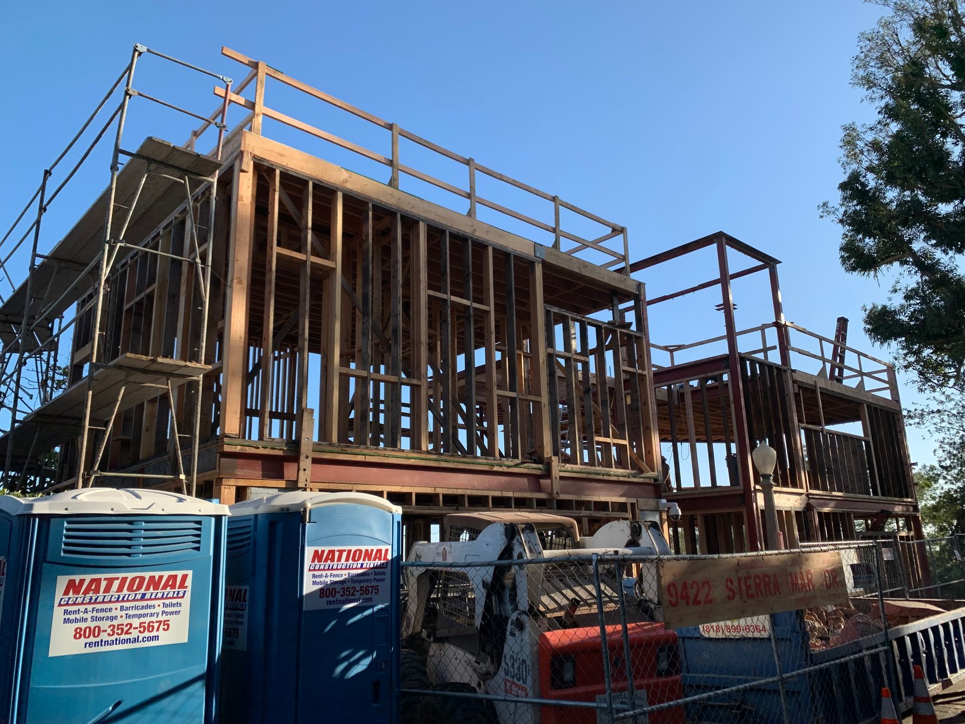 Two-story wooden building under construction with scaffolding and blue sky
