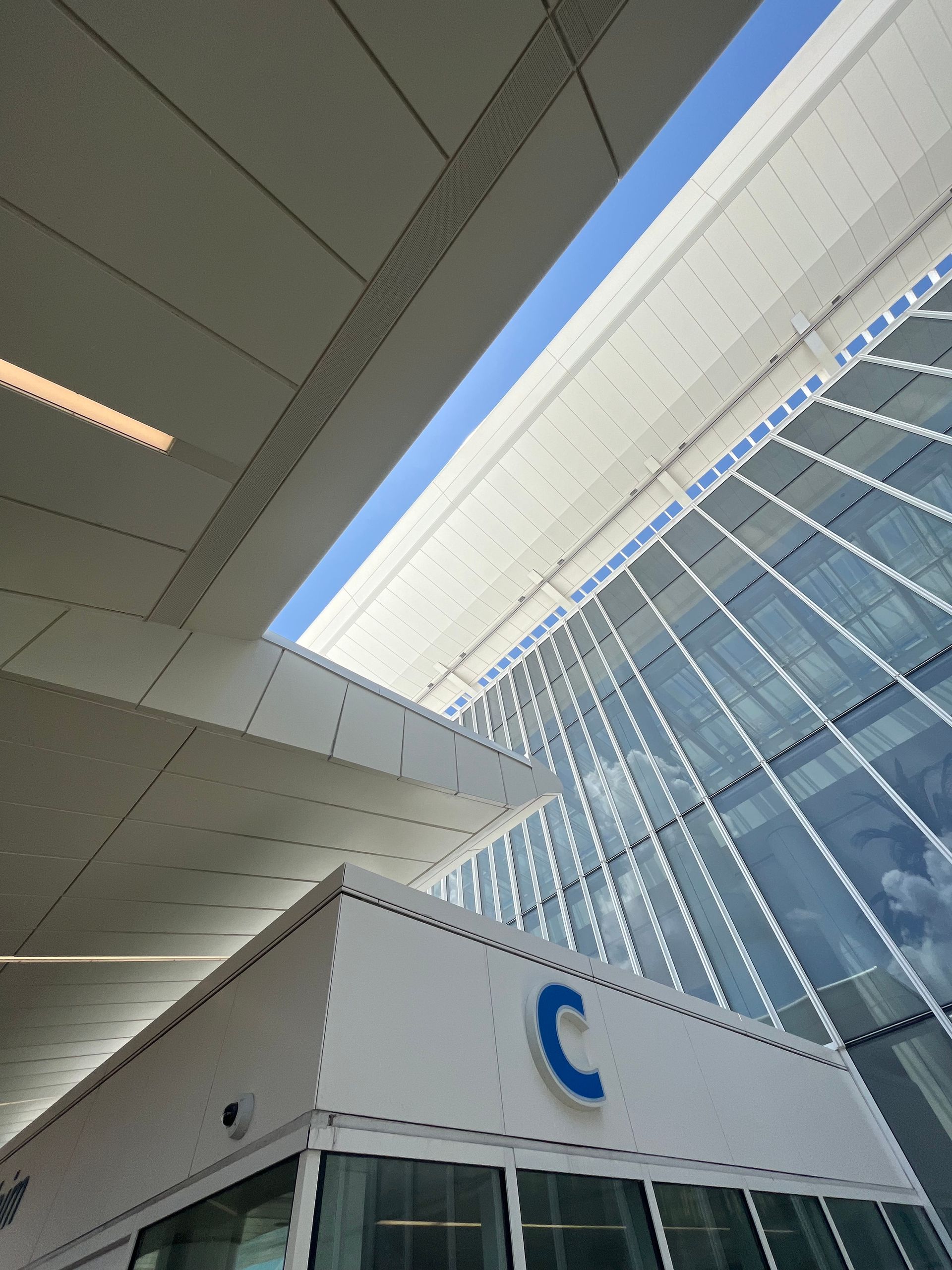 Modern building interior with skylight, glass facade, and a white sign with a blue “C” logo
