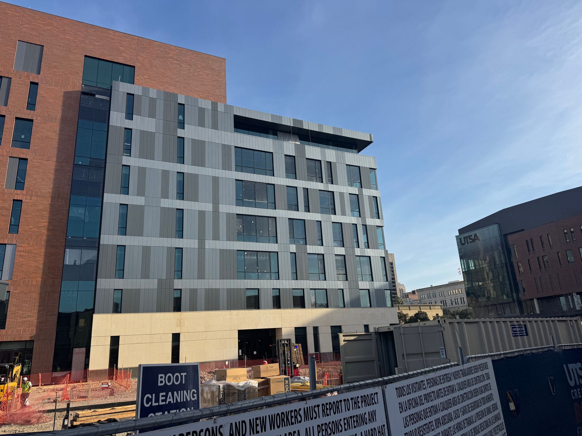 Modern glass office building beside a brick building under a clear blue sky
