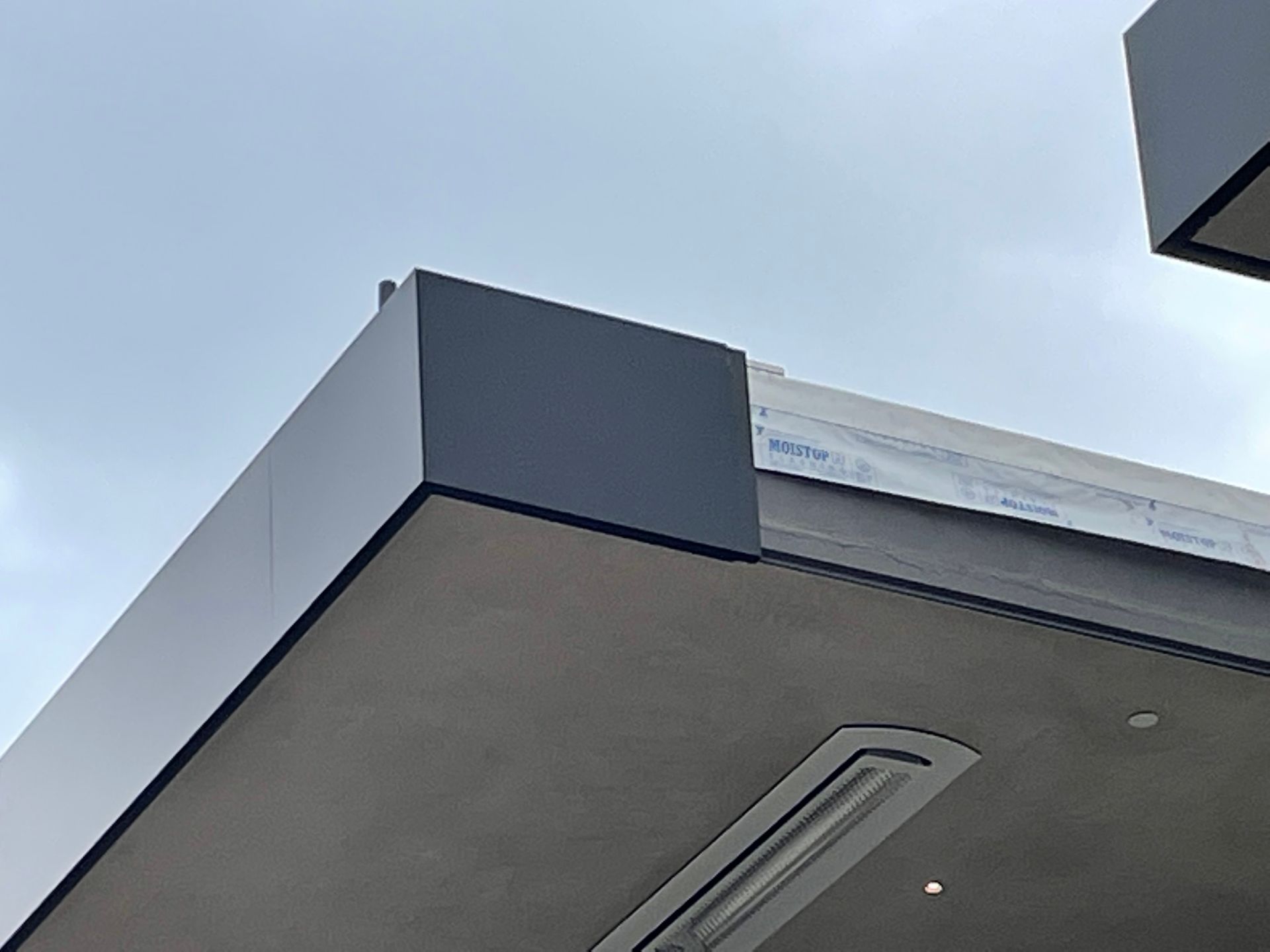 Modern building roofline with gray overhang against a cloudy sky