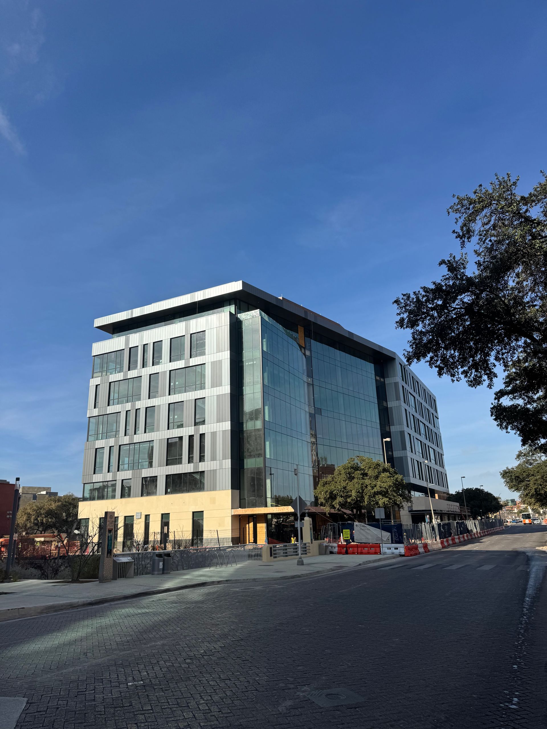Glass office building on a sloped street under a clear blue sky