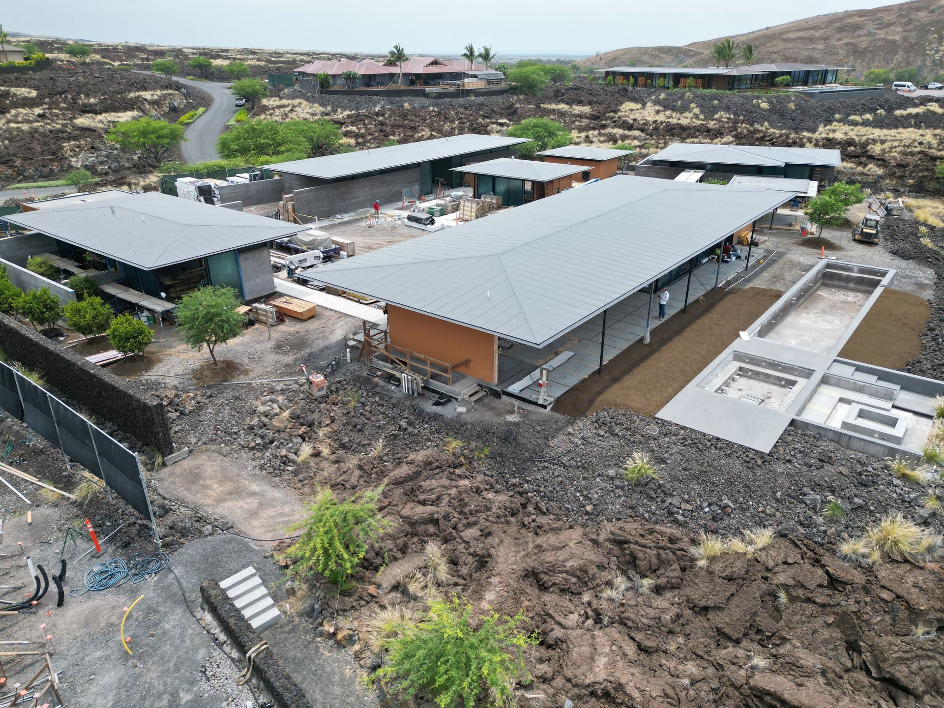 Aerial view of a hillside settlement with gray-roofed buildings and dirt roads.