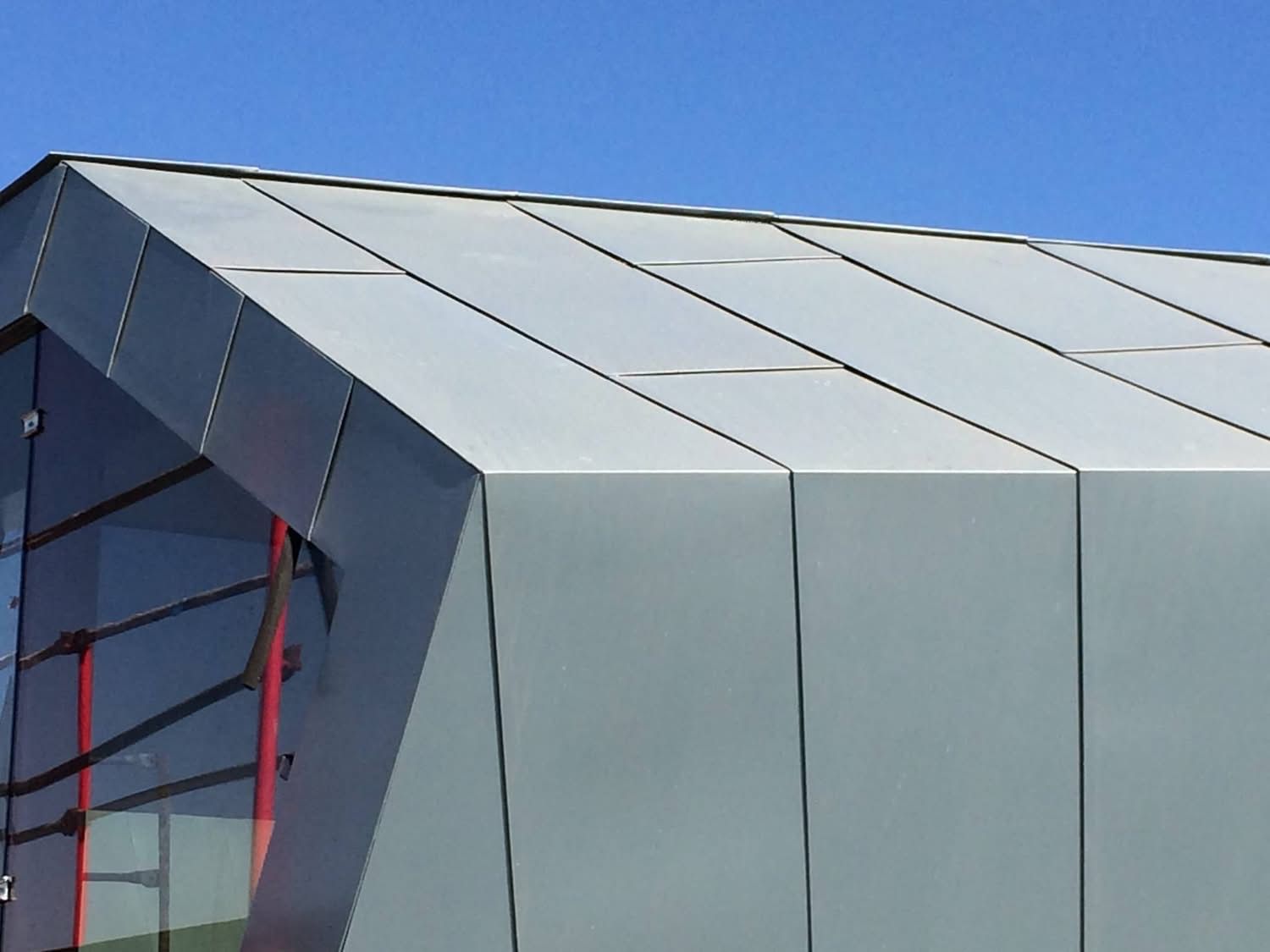 Modern building facade with silver metal panels and blue sky above