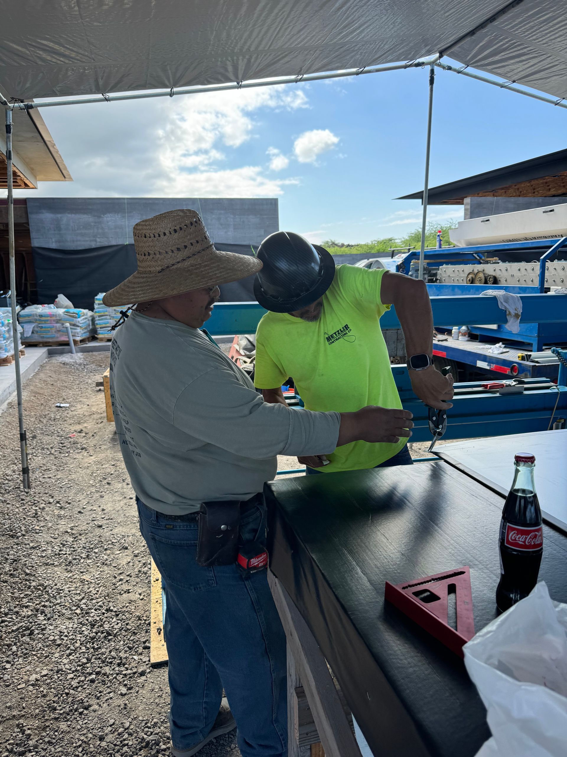 Two people under a canopy examining items on a table at an outdoor market.