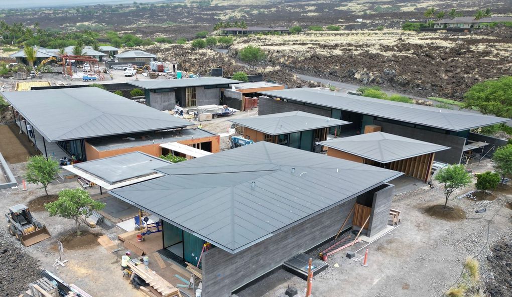 Aerial view of modern gray-roofed buildings in a rocky, sparsely vegetated landscape