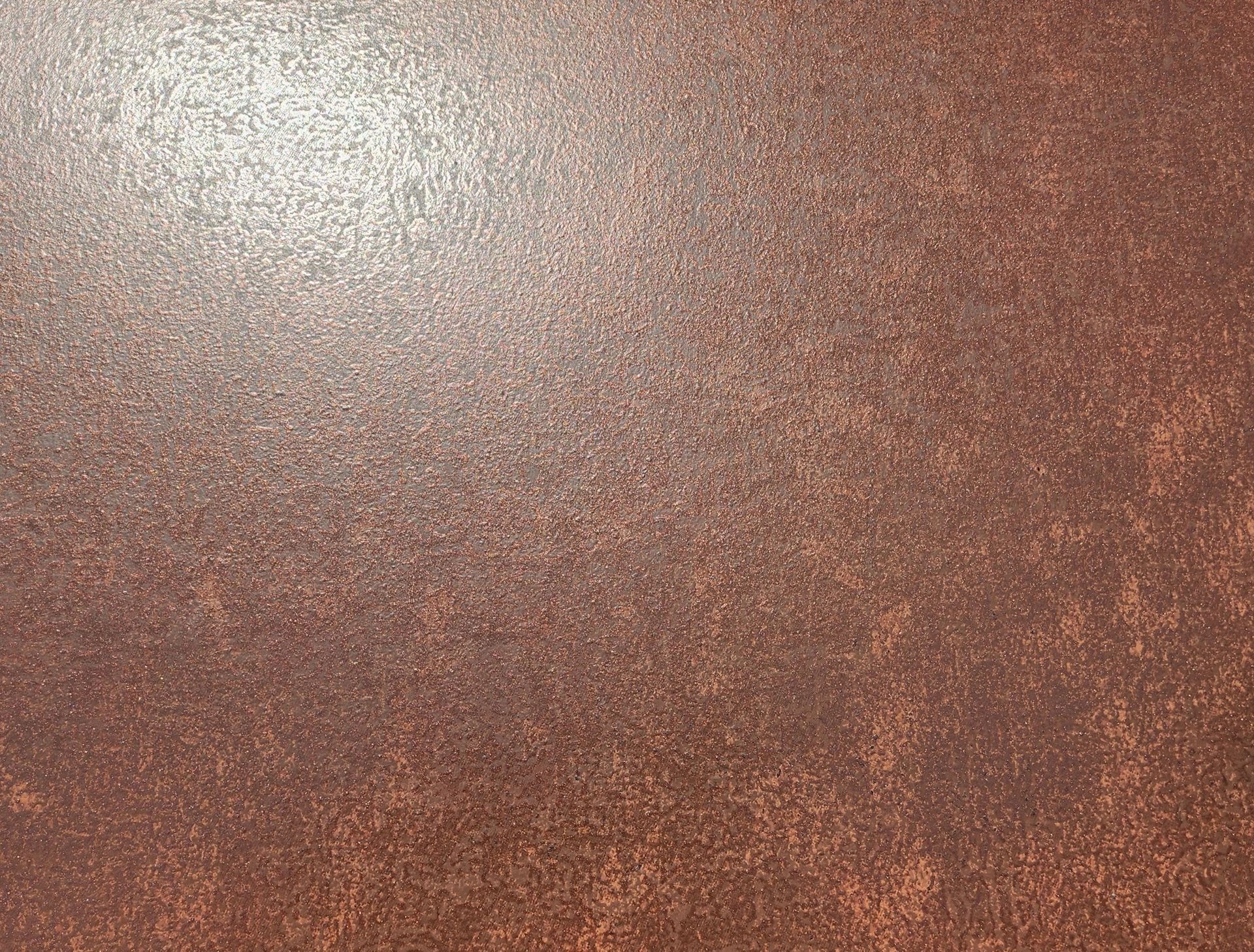 Close-up of a copper-brown textured surface with a bright light reflection in the upper left.