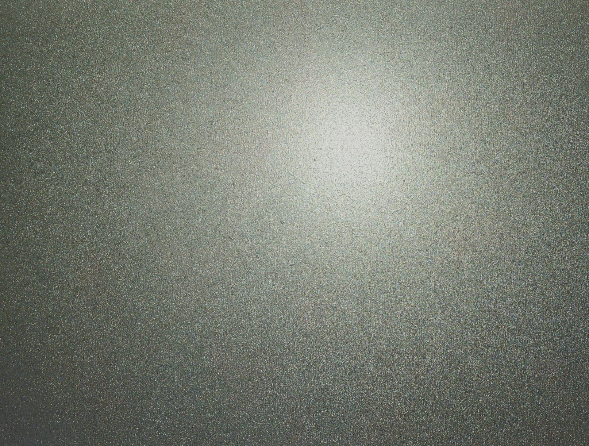 Blurred gray textured surface with a bright light spot near the top center