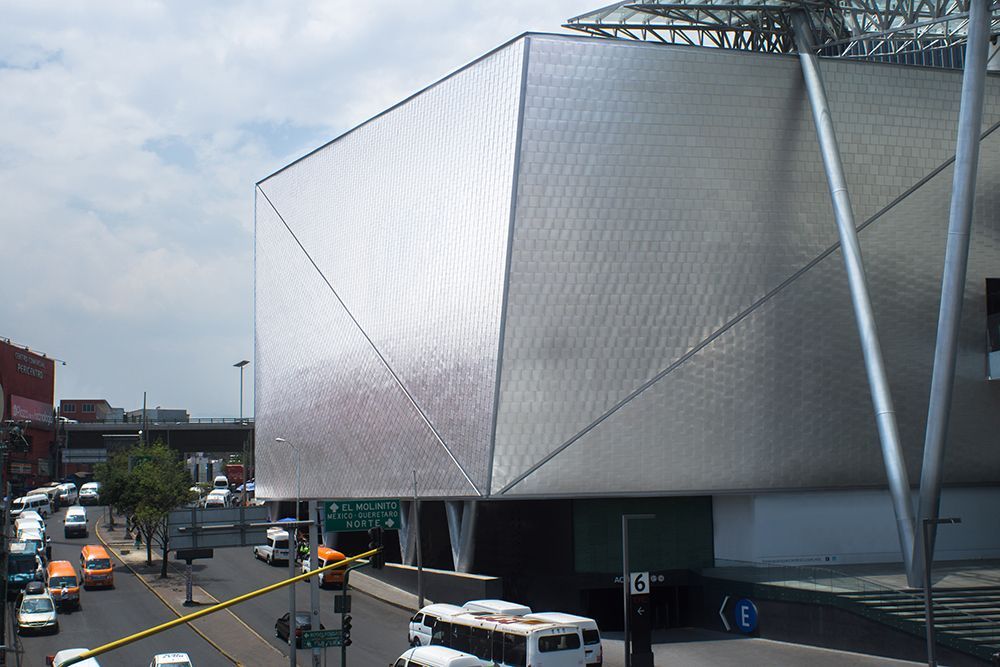 Modern silver building beside a busy city street with traffic and pedestrians