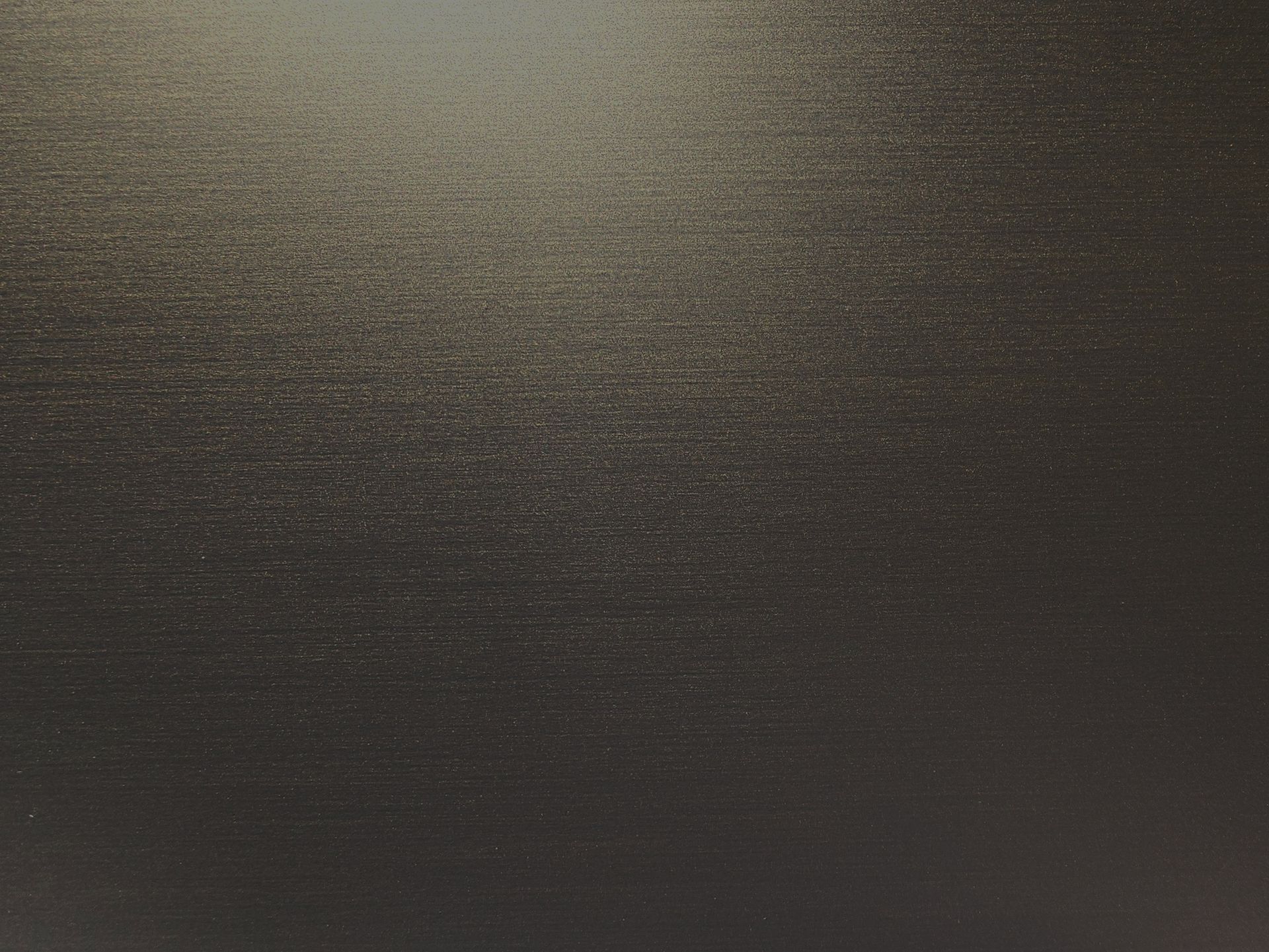 Dark textured surface with subtle horizontal lines and a faint light reflection at the top left