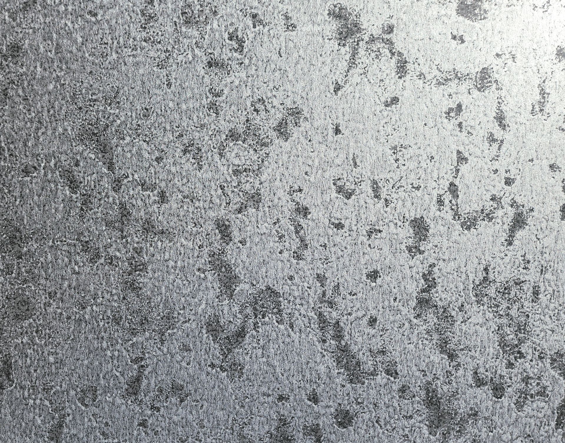 Gray speckled textured surface with scattered dark spots and smudges