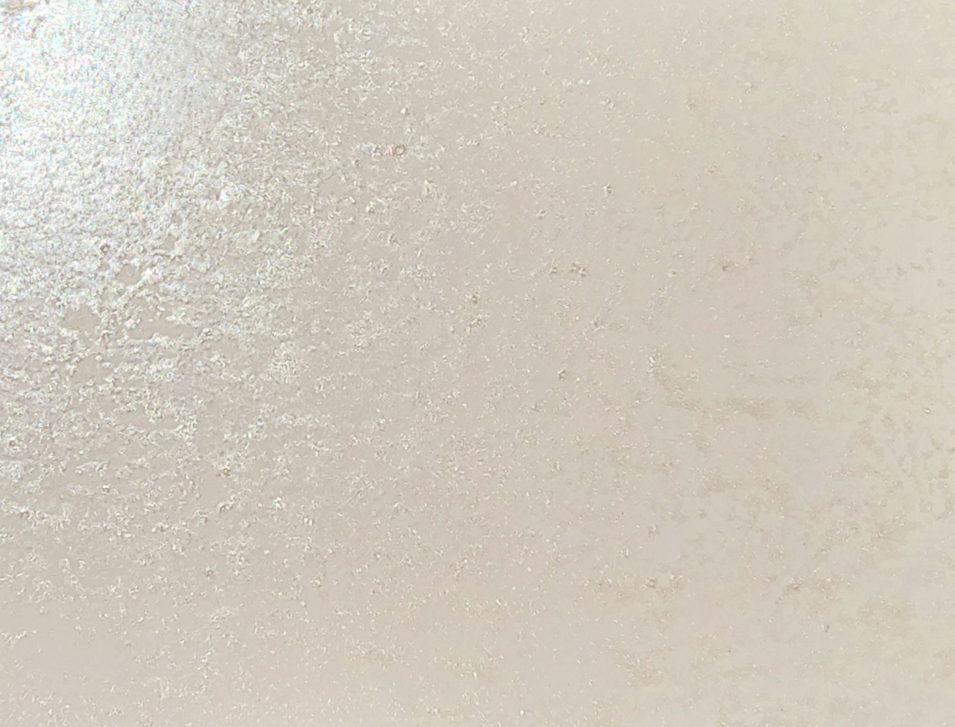 Close-up of a plain light beige textured surface with soft shadows
