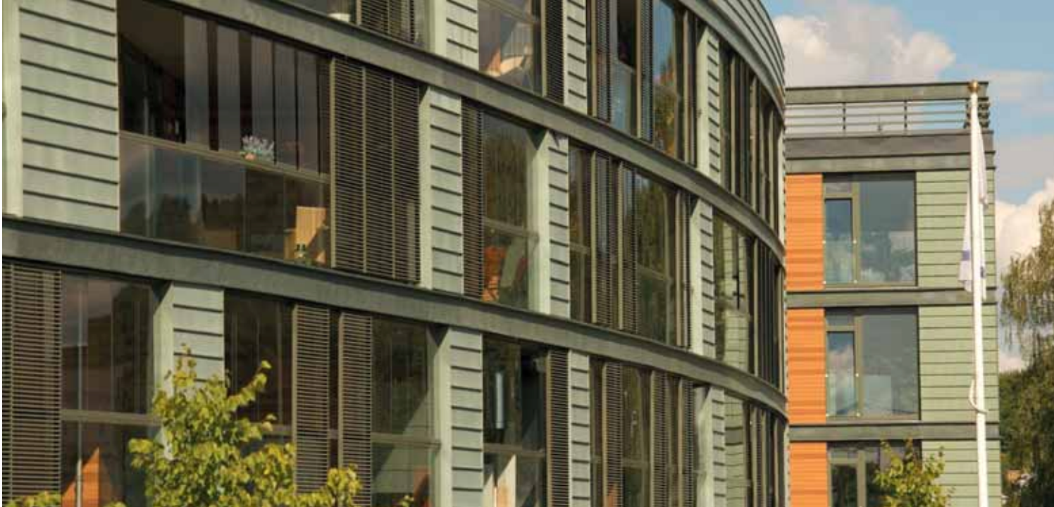Modern apartment building with curved glass balconies and orange-accented exterior panels