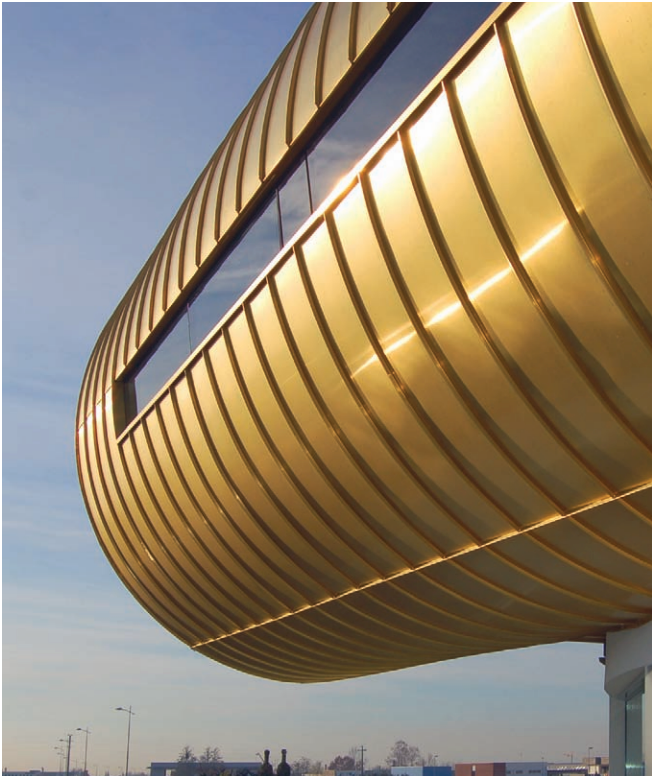 Curved golden modern building facade against a clear blue sky