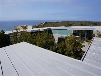 Modern coastal house with white roofs overlooking the ocean under a clear blue sky