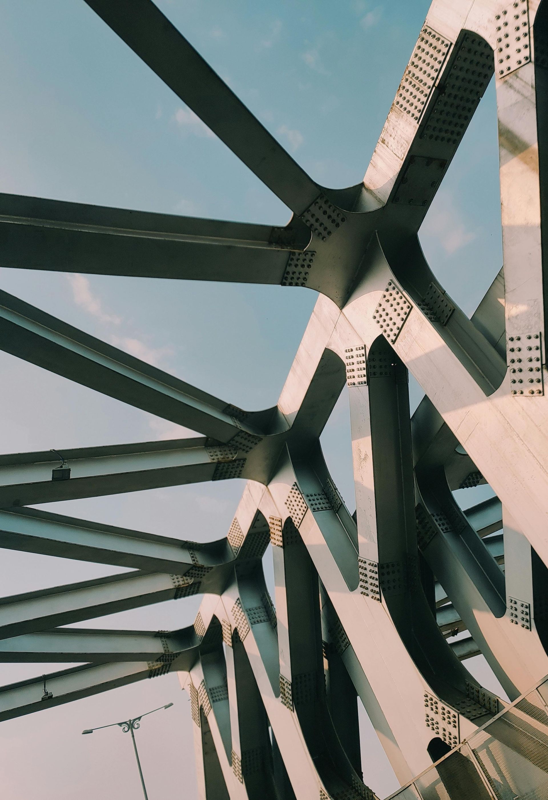 Steel bridge beams with a geometric pattern against the sky